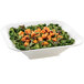 A white Tablecraft square bowl filled with salad with green leaves and orange cubes.