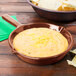 A Tablecraft copper fry pan with a bowl of cheese dip next to a bowl of tortilla chips.
