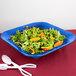 A blue Tablecraft square bowl filled with salad, carrots, and oranges.
