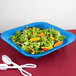 A blue Tablecraft square bowl filled with salad and oranges.