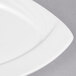 A close-up of a CAC Garden State white square porcelain plate with a curved edge.