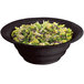 A black Tablecraft cast aluminum bowl filled with salad on a white background.