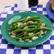 A Carlisle Meadow Green melamine salad plate with green beans and almonds.