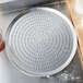 An American Metalcraft pizza pan with a perforated metal tray on it.