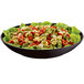 A Tablecraft midnight speckle pasta bowl filled with tortellini and lettuce on a table