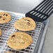 A Vollrath stainless steel cooling rack with chocolate chip cookies on it.