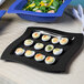 A black Tablecraft square tray with deviled eggs and salad on a counter.