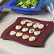 A Tablecraft maroon speckle cast aluminum tray with deviled eggs and salad on it.