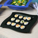 A black Tablecraft cast aluminum platter with deviled eggs and salad on it.
