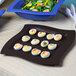 A Tablecraft midnight speckle square platter with deviled eggs and salad on a table.