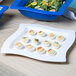 A Tablecraft white square cast aluminum platter with deviled eggs and salad.