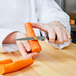 A person using a Victorinox chef knife to slice a carrot.