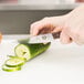 A person cutting a cucumber with a Victorinox steak knife.