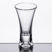 A close-up of a Thunder Group clear plastic flared dessert shot glass on a table with a reflection.