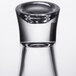 A close-up of a clear plastic flared dessert shot glass with a small hole in the bottom.