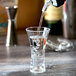 A Thunder Group plastic flared dessert shot glass filled with clear liquid.