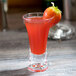 A Thunder Group plastic flared dessert shot glass filled with a red drink and topped with a strawberry