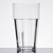 A close-up of a Thunder Group clear polycarbonate tumbler filled with water on a table.