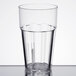 A close-up of a Thunder Group clear polycarbonate tumbler with water in it on a table.