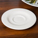 A Homer Laughlin Kensington Ameriwhite saucer on a table with asparagus on it.