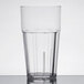 A clear polycarbonate tumbler with a black rim on a table with water in it.