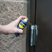 A person using WD-40 spray to lubricate a door hinge.