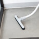 A ProTeam backpack vacuum cleaner on the floor of a white room.