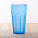 A blue Thunder Group polycarbonate tumbler with ice on a wood surface.