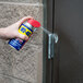 A hand holding a WD-40 spray can with a smart straw spraying a door handle.