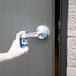 A hand holding a WD-40 spray can opening a door handle.