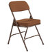 A brown National Public Seating metal folding chair with an antique gold fabric padded seat.