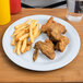 A white Carlisle melamine plate with fried chicken and fries.