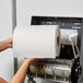 A woman's hands holding a roll of Lavex white hardwound paper towel.