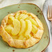 A pastry with Regal sliced apples on top of it on a plate.