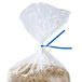 A plastic bag with rice in it closed with a blue paper twist tie.