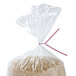 A bag of rice with a red and white striped paper twist tie.