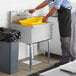A person in a black apron using a Steelton commercial utility sink.