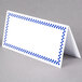 A white rectangular deli tent card with a blue checkered border and space to write on.