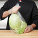 A person holding an LK Packaging plastic food bag filled with lettuce.