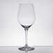 A close-up of a clear Spiegelau Authentis red wine glass on a table with a reflection.