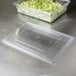 A clear Rubbermaid food storage box lid on a plastic container of lettuce.