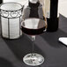 A close-up of a Spiegelau Bordeaux wine glass filled with red wine on a table.