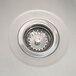 A close-up of a stainless steel sink drain with a circular object with a light in it.