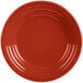 A close-up of a red Fiesta luncheon plate with a circle pattern on the rim.