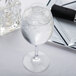 A Spiegelau red wine glass filled with ice water on a white background.