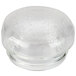 A clear glass container with a round top over a close-up of a white surface.