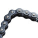 A close-up of a black and silver drive chain for a Nemco hot dog grill.