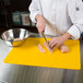A chef cutting chicken on a Tablecraft flexible cutting board.