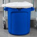 A Rubbermaid blue plastic BRUTE trash can with a lid on it.