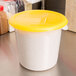 A Rubbermaid white polyethylene food storage container with a yellow lid.